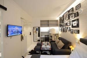 a living room with a couch and a tv on a wall at Résidence Voûte in Paris