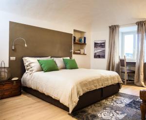 1 dormitorio con 1 cama grande con almohadas verdes en Virgula B&B en Cuneo
