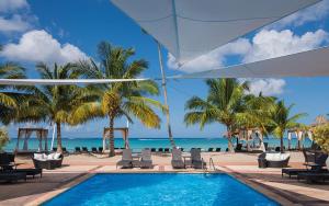 a swimming pool next to the beach with palm trees at The blue lagoon of the Caribbean Sea. Velero 205.Cadaques Caribe in La Fragata
