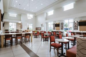 a dining room with tables and chairs and windows at Holiday Inn Express & Suites Boynton Beach East, an IHG Hotel in Boynton Beach