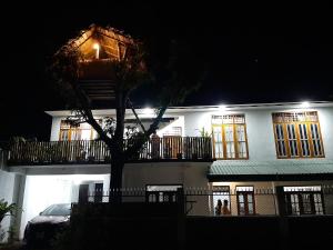 una casa bianca con un albero di fronte di notte di Mangohut Joy a Anuradhapura