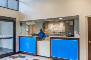 un hombre parado en un mostrador en una oficina con signos azules en Holiday Inn Express Hotel & Suites Fort Payne by IHG, en Fort Payne 39 fotos más