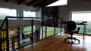 una oficina con escritorio y silla en una habitación con ventanas en Casa en las Sierras de Córdoba en Unquillo