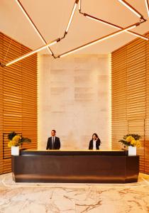 two people sitting at a reception desk in a lobby at The William Vale in Brooklyn