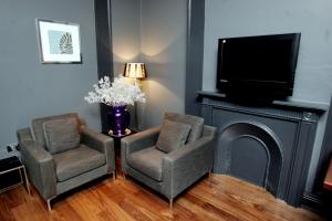 a living room with two chairs and a tv at Boutique 25 in Skipton