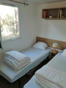ラ・パルミールにあるMobile-Home climatisé 4 personnesの窓付きの客室で、ベッド2台が備わります。