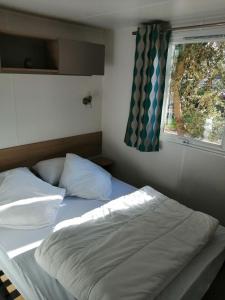 ラ・パルミールにあるMobile-Home climatisé 4 personnesの窓とベッドサイドシックスが備わるドミトリールームのベッド1台分です。