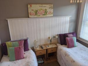 a bedroom with two beds with pillows and a table at Aqua Bay Guest House in Herne Bay