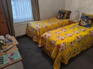 a bedroom with two beds with yellow sheets and flowers at Aqua Bay Guest House in Herne Bay