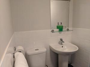 a white bathroom with a toilet and a sink at Aqua Bay Guest House in Herne Bay