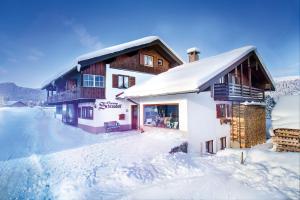 a building with snow on the ground next to at Ferienwohnungen Gästehaus Schraudolf in Oberstdorf
