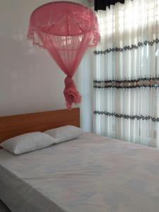 una camera da letto con un letto e un ombrello rosa di Mangohut Joy a Anuradhapura