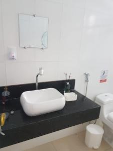 La salle de bains est pourvue d'un lavabo blanc sur un comptoir noir. dans l'établissement Residencial e Pousada Sea La Vie, à Maragogi