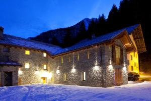 un edificio in pietra con luci nella neve di notte di Drésalwoald a Gressoney-Saint-Jean