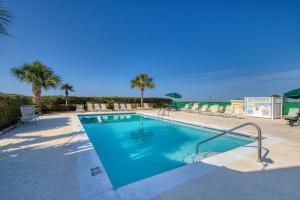 a large swimming pool with palm trees in a resort at Plantation East III in Gulf Shores