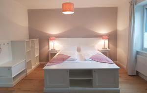 a bedroom with a white bed with two lamps at Domizil Gols, Studios Am Anger in Gols