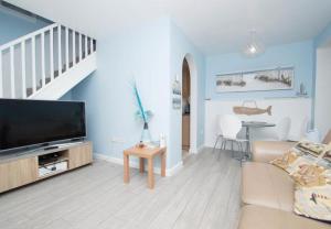 sala de estar con TV de pantalla plana y sofá en Bo's Holiday Cottage, en Eastbourne
