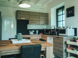 a kitchen with a wooden table with chairs and a microwave at La Belle Landaise 1809 Gîte Arridoulet 1 in Peyrehorade