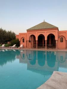 ein großer Wasserpool mit einem Gebäude im Hintergrund in der Unterkunft Villa avec piscine a Marrakech in Marrakesch