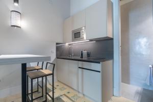 a kitchen with a counter with stools and a sink at Apartamentos Caminante del Agua in Seville