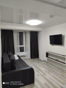 a living room with a black couch and a flat screen tv at Апарт-Отель - 12 шагов к морю, ЖК Орион in Odesa