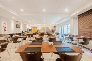 a dining room with tables and chairs and windows at Slim Hotel Curitiba Av das Torres in Curitiba +39 photos