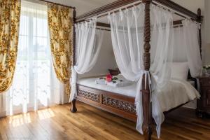 a bedroom with a canopy bed with white curtains at Maison d'hôtes de charme La Rose de Ducey près du Mont Saint Michel in Ducey
