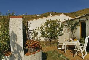 een patio met een tafel en stoelen en een huis bij Cortijo Lagar de Luisa in Borge