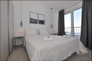a white bedroom with a large bed and a balcony at Apartmani Miranda in Drasnice