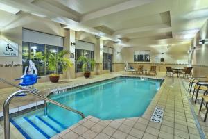 een zwembad in een hotel met tafels en stoelen bij Holiday Inn & Suites Green Bay Stadium, an IHG Hotel in Green Bay