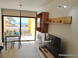 sala de estar con TV, mesa y comedor en Ocean View Playa la Arena by HelloApartments, en Puerto de Santiago