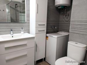 Un baño con lavabo, inodoro y espejo. en Ocean View Playa la Arena by HelloApartments, en Puerto de Santiago 23 fotos más