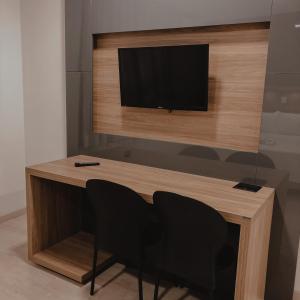 a desk with two chairs and a television on a wall at Petri Plaza Hotel in Francisco Beltrão