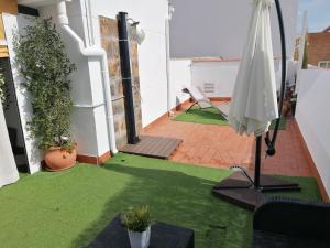 a balcony with a green lawn and an umbrella at Ático Azahar in Córdoba