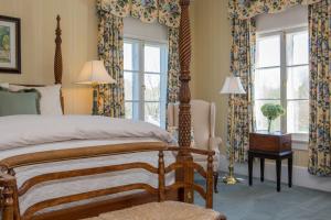 a bedroom with a bed and windows with curtains at Inn at Warner Hall in Gloucester