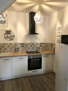 a kitchen with white cabinets and a stove top oven at Les jardins d Honfleur et sa terrasse privative in Honfleur