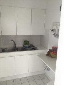 a kitchen with white cabinets and a sink at Zeezicht in Westende
