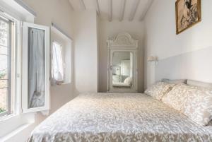 a white bedroom with a bed and a mirror at Happy Florence San Niccolò n.2 in Florence