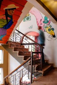 a person walking down a staircase with a painting on the wall at Hostel Running Chaski in Cochabamba