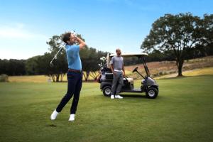 Dois homens a jogar golfe com um carrinho de golfe. em Omni Barton Creek Resort and Spa Austin em Austin