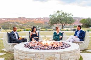 un grupo de personas sentadas alrededor de una hoguera en Omni Barton Creek Resort and Spa Austin en Austin
