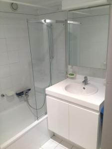 een witte badkamer met een wastafel en een douche bij Zeezicht in Middelkerke