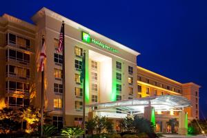 a hotel with a green sign on the front of it at Holiday Inn Hotel & Suites - Orange Park - Wells Rd. in Orange Park