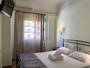 Hotel Ionion في بيرايوس: غرفة نوم بسرير ومخدات بيضاء ونافذة