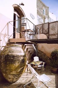 eine Terrasse mit einer großen Vase, 2 Stühlen und einem Tisch in der Unterkunft La Casa Grande in Arcos de la Frontera