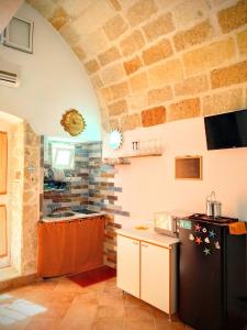 Il comprend une cuisine dotée d'un réfrigérateur noir et d'un mur en pierre. dans l'établissement Dimora la Sirenetta, à Polignano a Mare