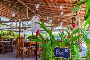 a restaurant with tables and chairs and a sign at Pousada Portal do Cacau-Petfriendly in Camburi