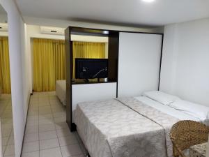 1 dormitorio con 1 cama y TV de pantalla plana en Pipa's Bay Apartamentos, en Pipa