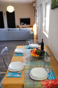 a table with plates and wine glasses and vegetables on it at Luxury Apartment RougeMarin in Pakoštane