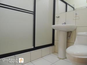 y baño con lavabo y aseo. en Hostal Guayllabamba, en Quito